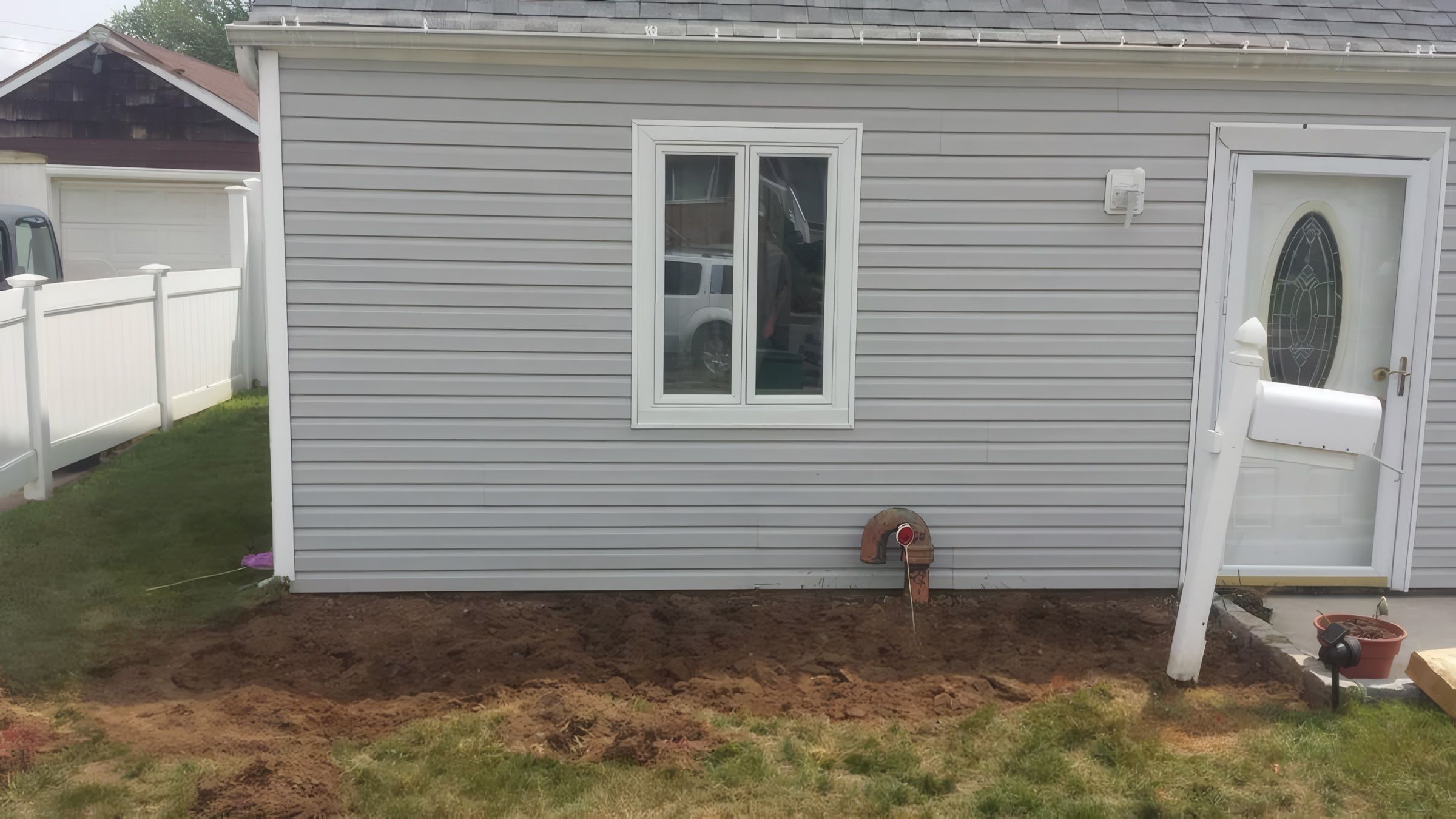 A bare soil bed along a house wall before planting