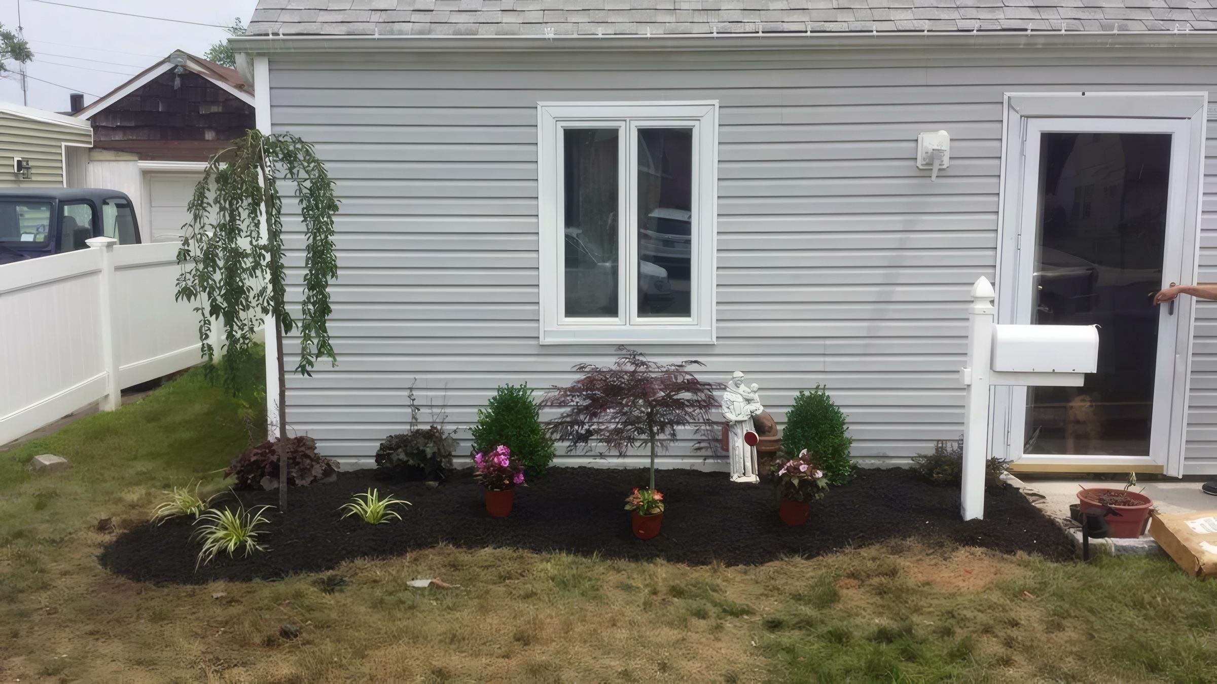The same bed planted with a weeping tree and shrubs, finished in mulch