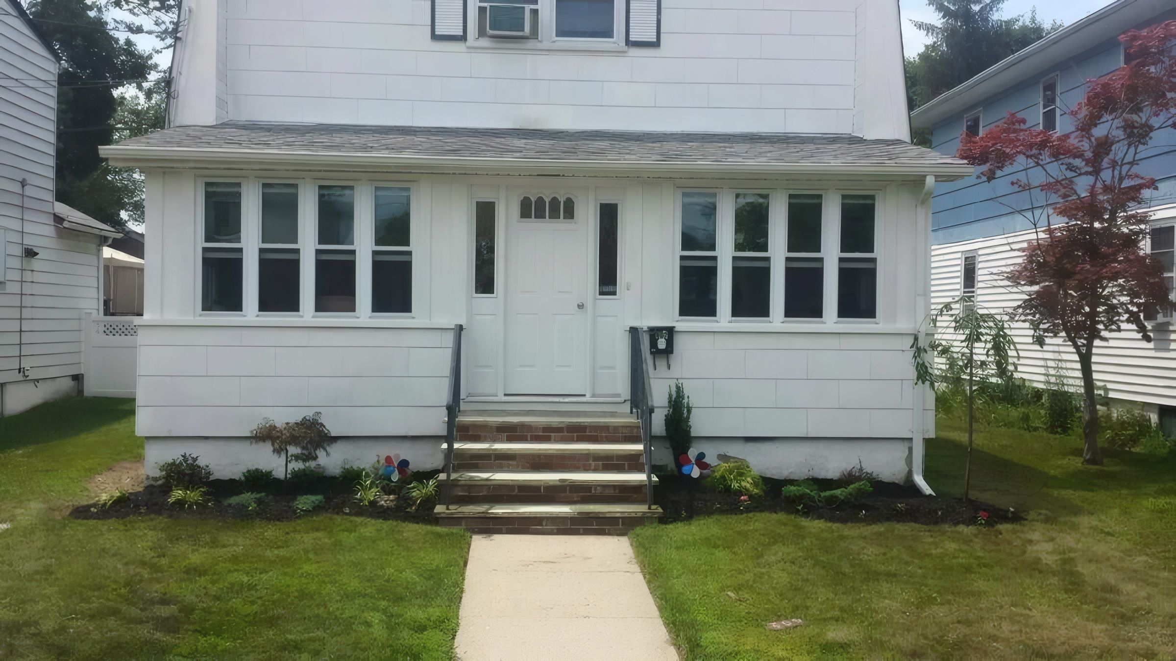 The same house front with fresh mulch and new plantings along the foundation