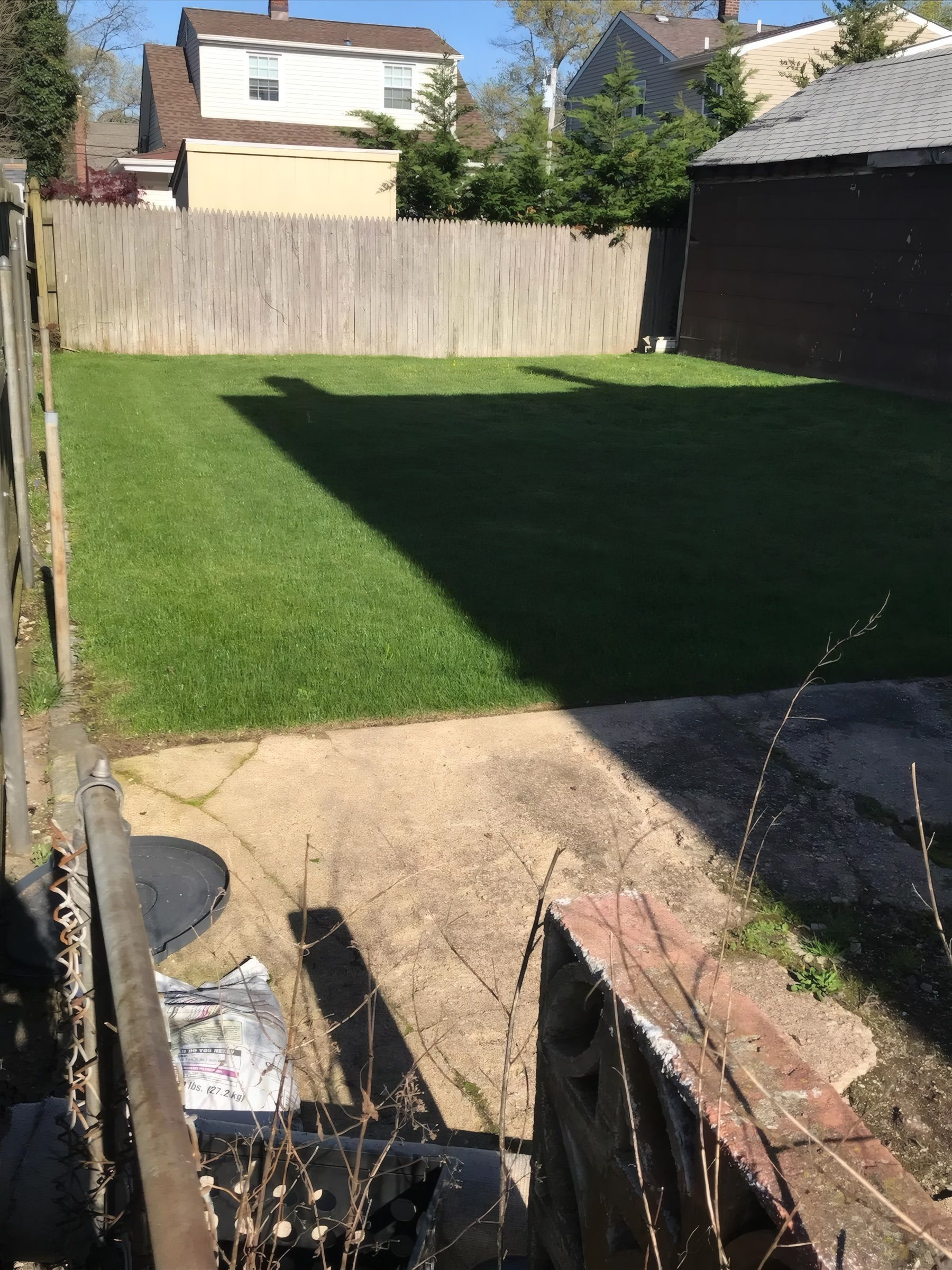 A thick green backyard lawn in front of the same wooden fence