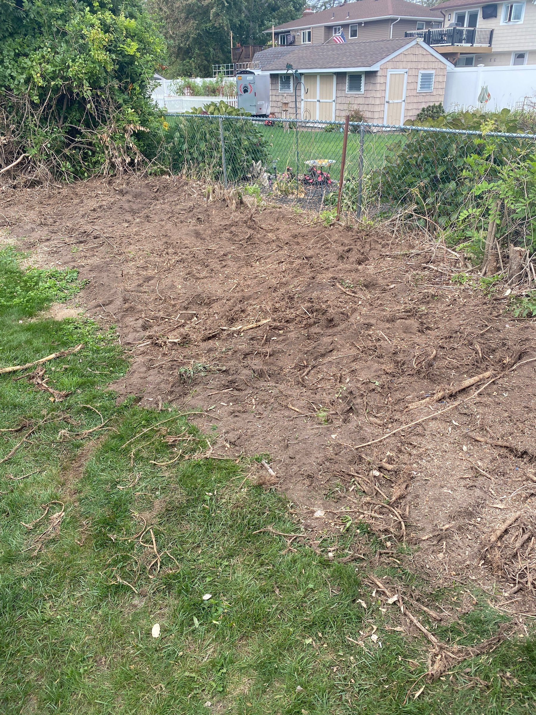 Backyard strip cleared to bare soil along a chain-link fence