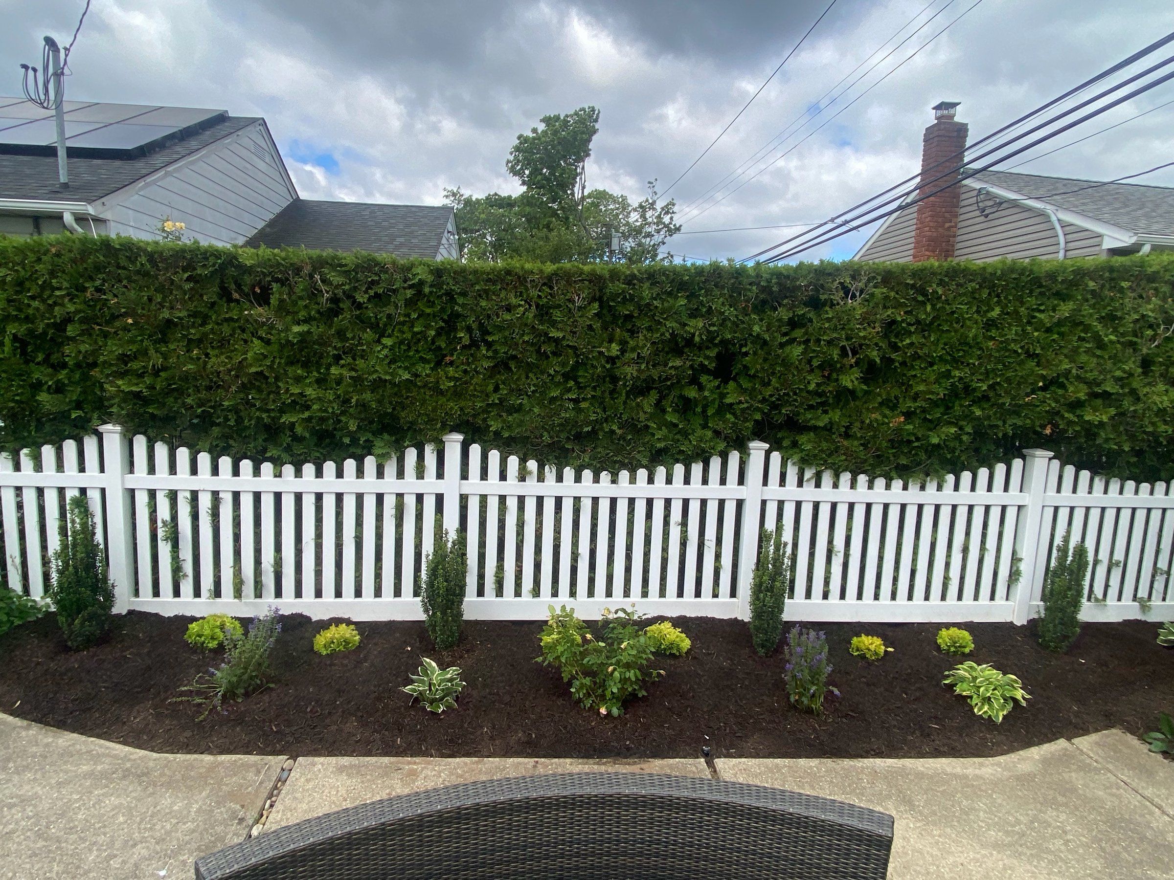 Straight-on view of the planted, mulched bed along the picket fence