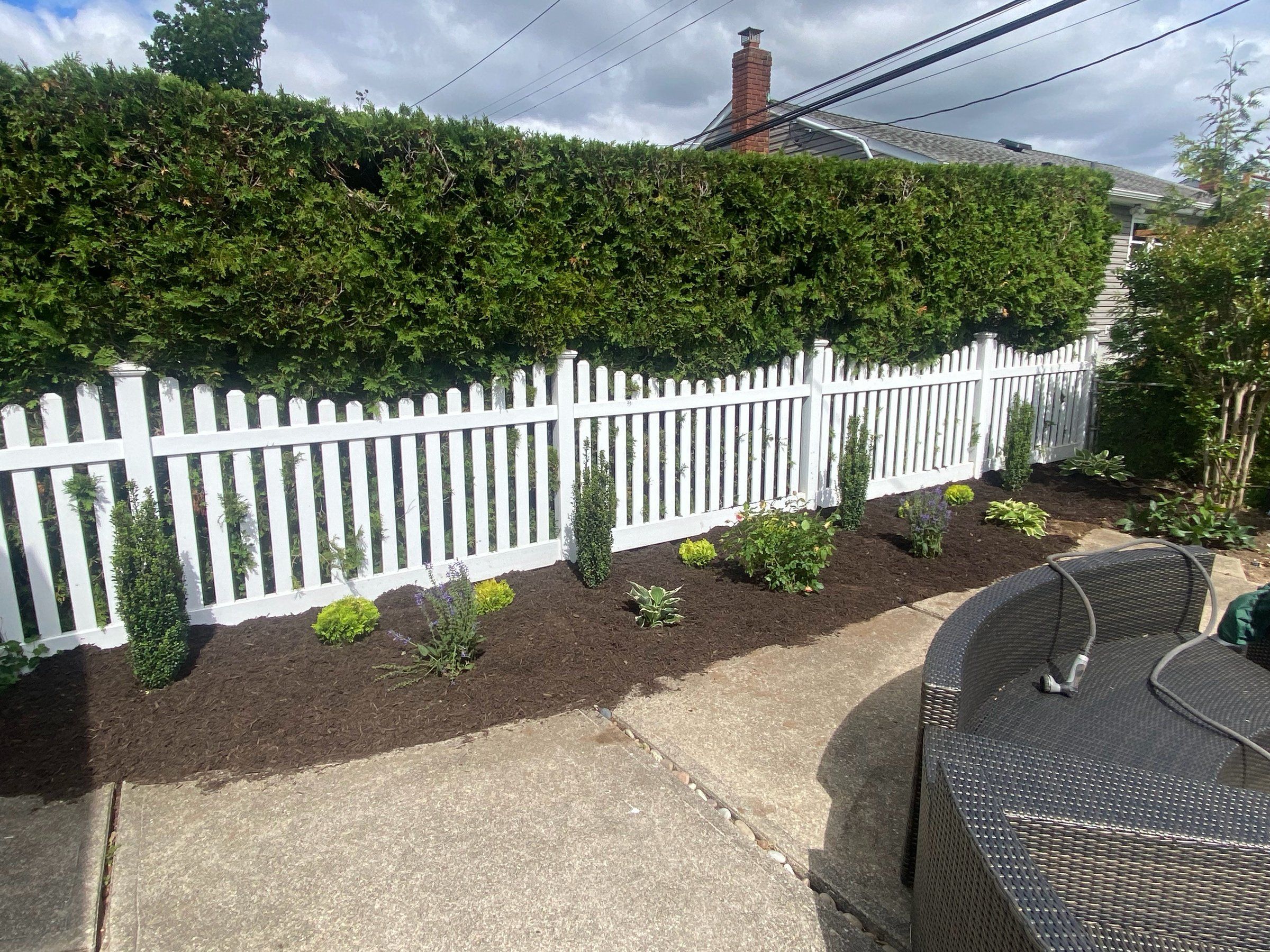 The bed along the picket fence planted and mulched