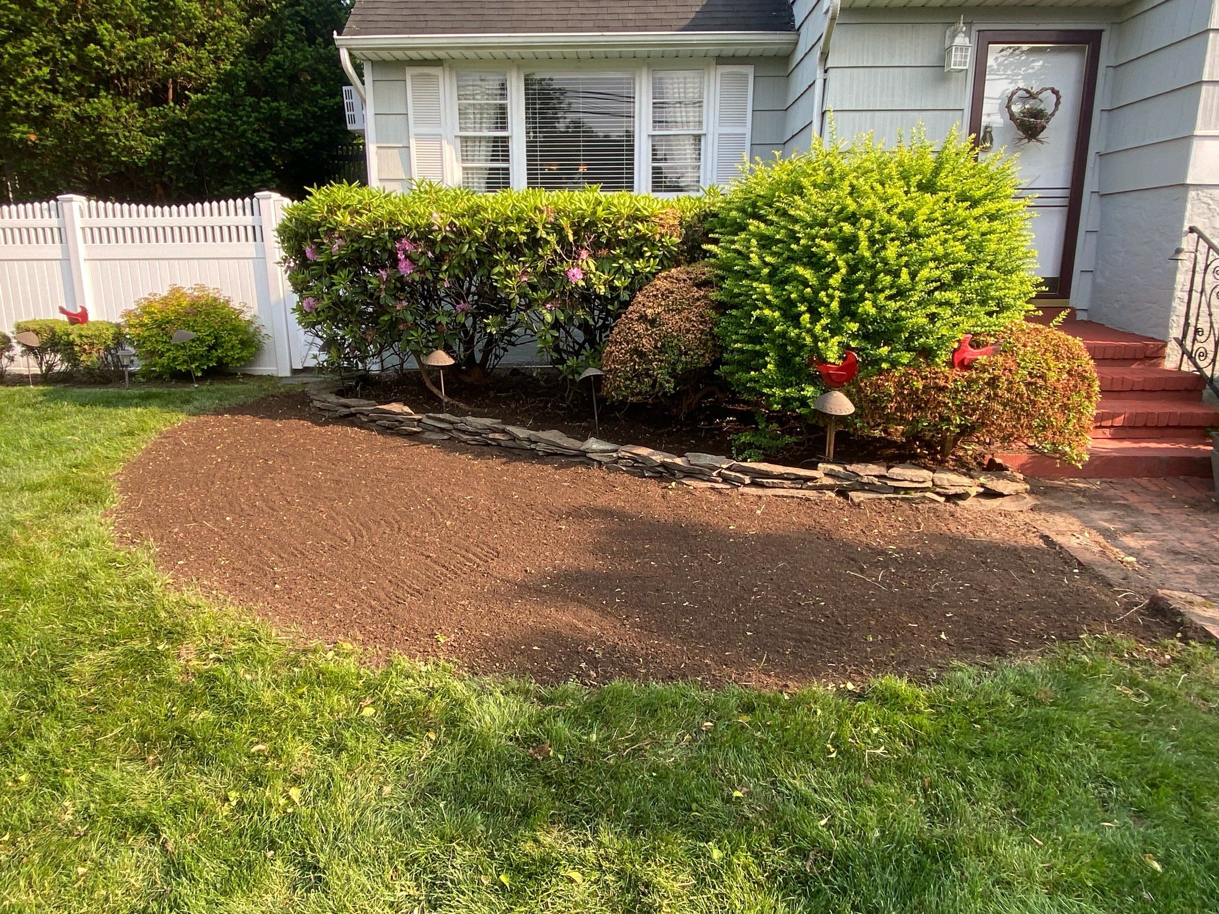 The same bed cleared to raked soil with a stacked-stone edge
