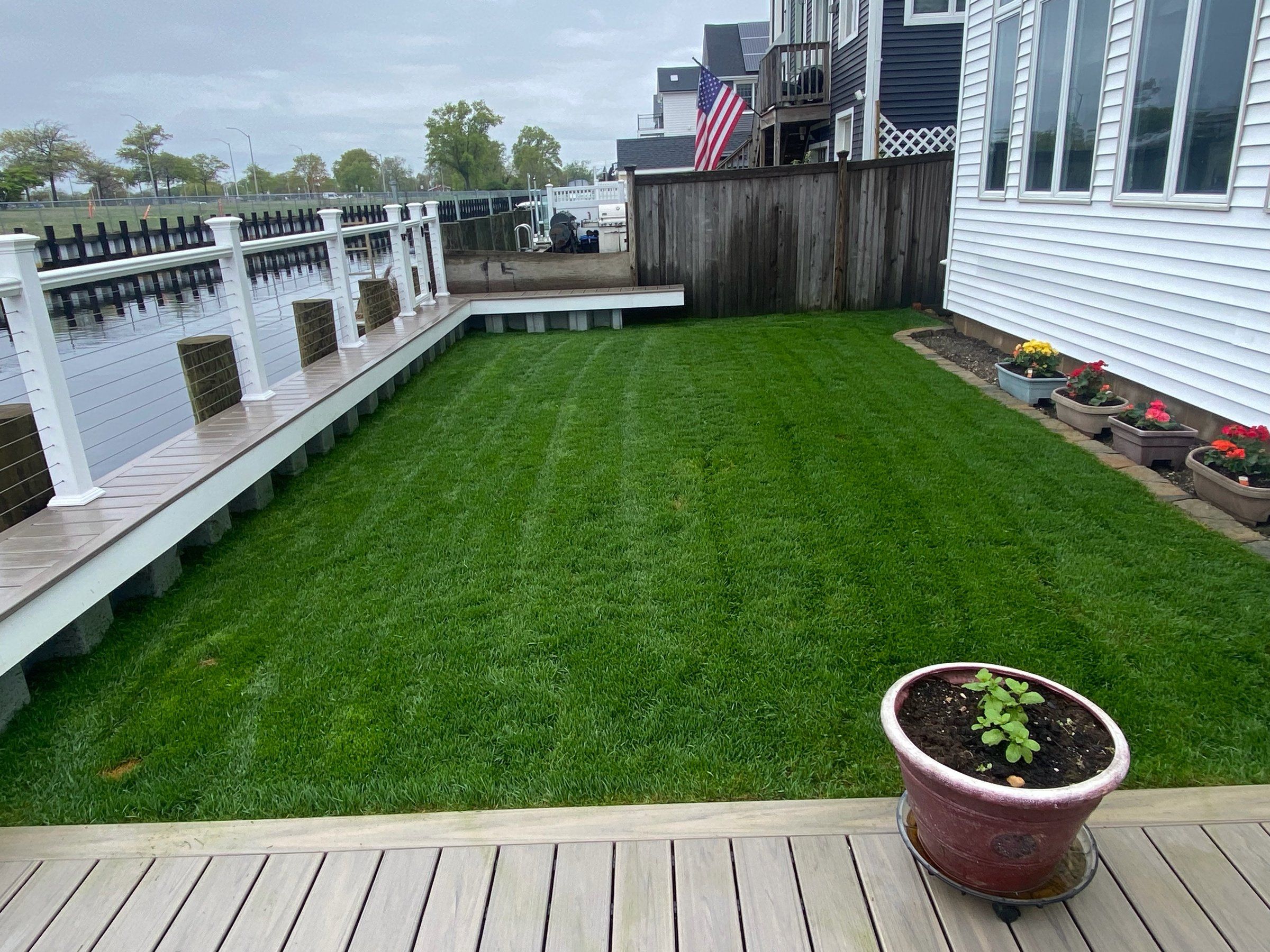 The same yard a month after sodding: a striped green lawn with flowers in the brick-edged bed along the house