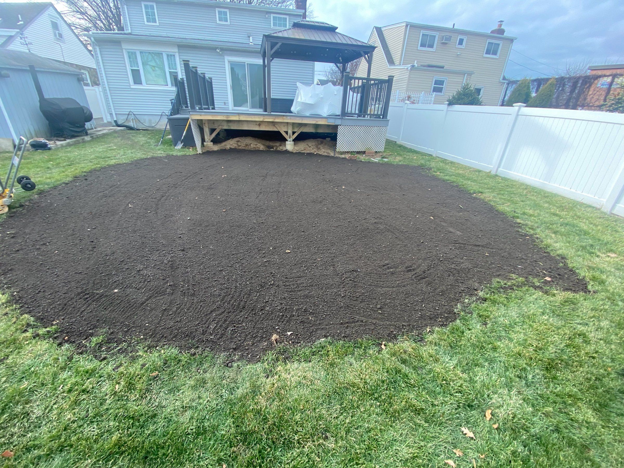 Round patch of fresh topsoil graded level in the lawn where a pool stood