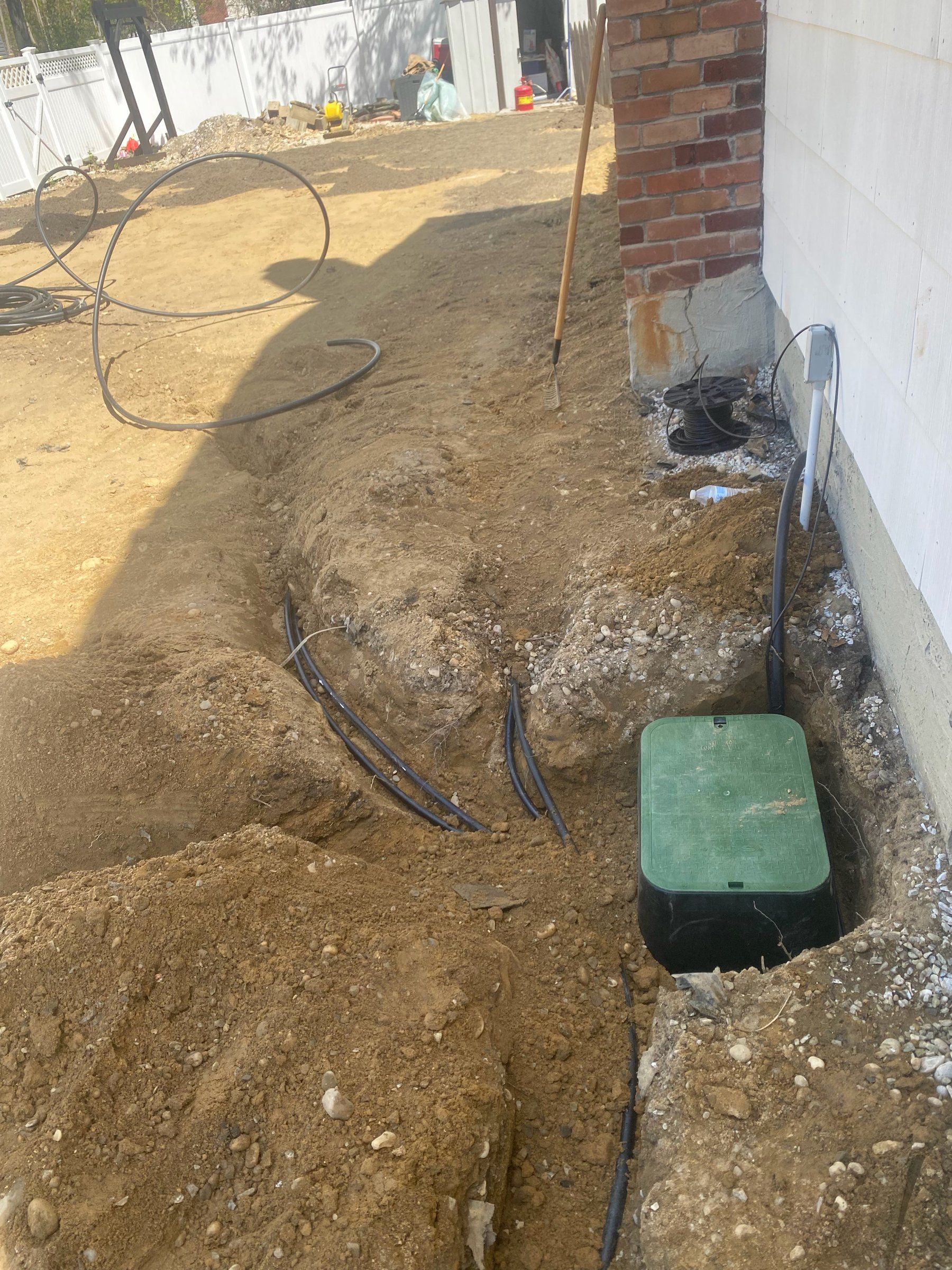 Sprinkler trench and a new green valve box beside the house